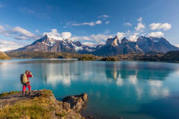 Fotogranfo sacando fotos al lago pehoe con las torres del paine de fondo en la patagonia chilena